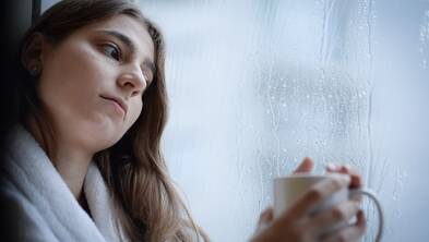  Smutna kobieta w szlafroku w domu, w deszczowy, chłodny dzień. Zdj. ilustracyjne. Fot. PAP/Jacek Turczyk
