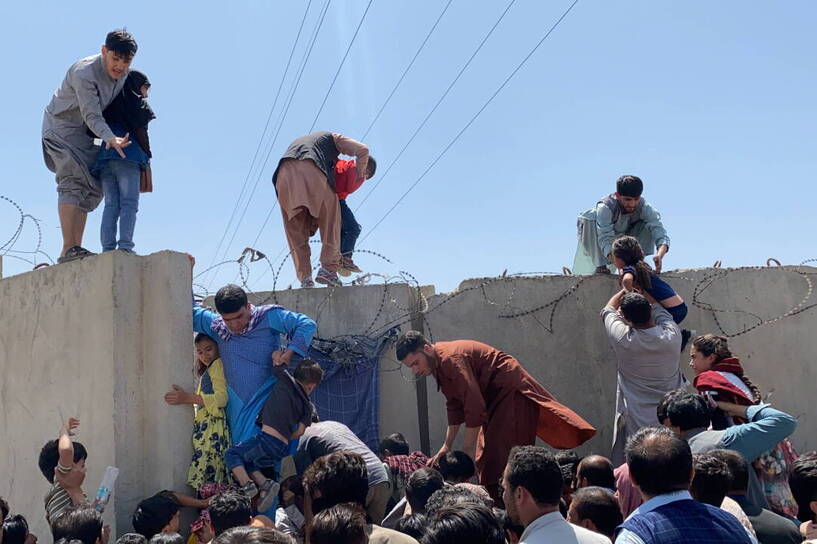  Ludzie walczą o przekroczenie muru granicznego międzynarodowego lotniska Hamida Karzaja, aby uciec z kraju po plotkach, że obce kraje ewakuują ludzi nawet bez wiz, po tym, jak talibowie przejęli kontrolę nad Kabulem w Afganistanie. Fot. PAP/EPA/STRINGER