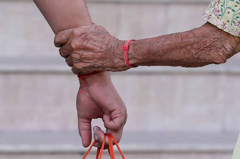 Ręka starszej osoby trzyma rękę młodszejFot. PAP/EPA/HARISH TYAGI 