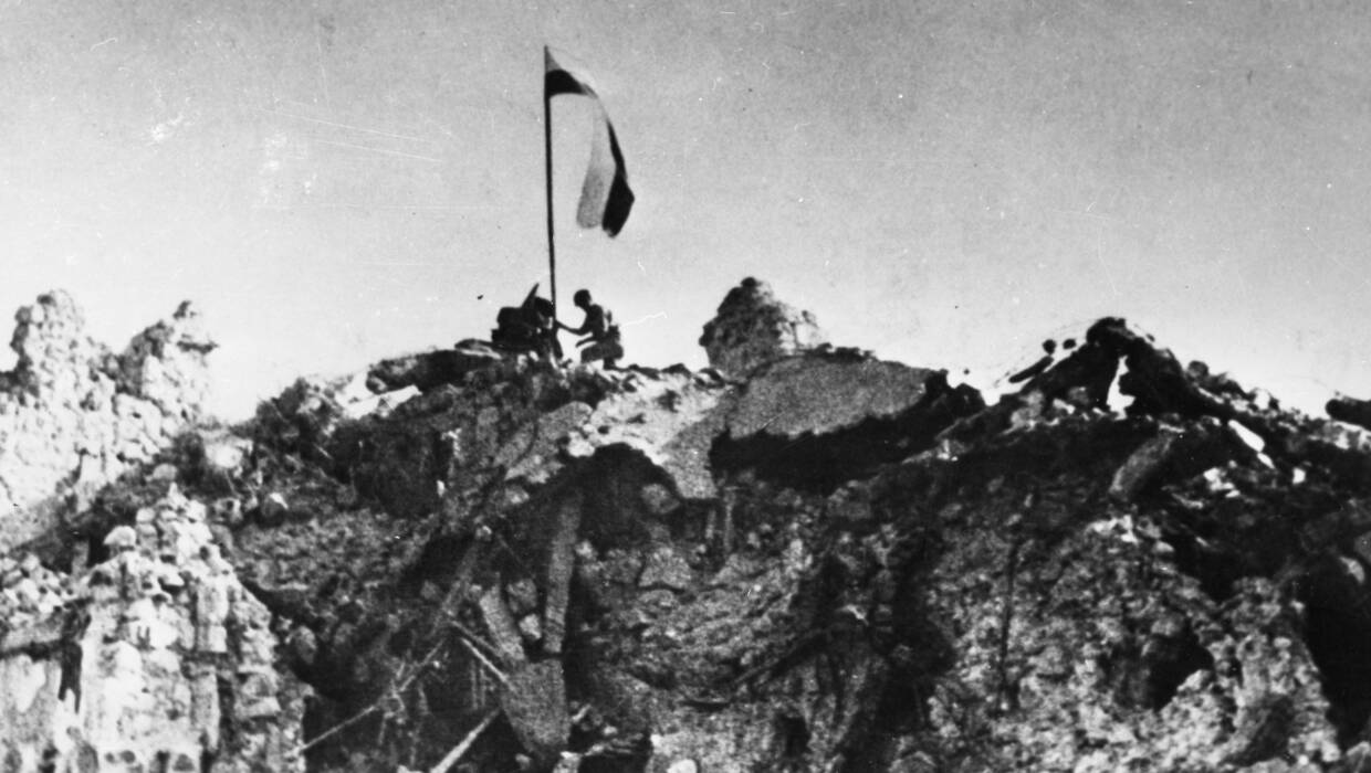 Po trzygodzinnej, zwycięskiej walce, patrol z 12. Pułku Ułanów Podolskich zatyka polską flagę nad rumowiskiem klasztoru Monte Cassino. Fot. PAP/CAF